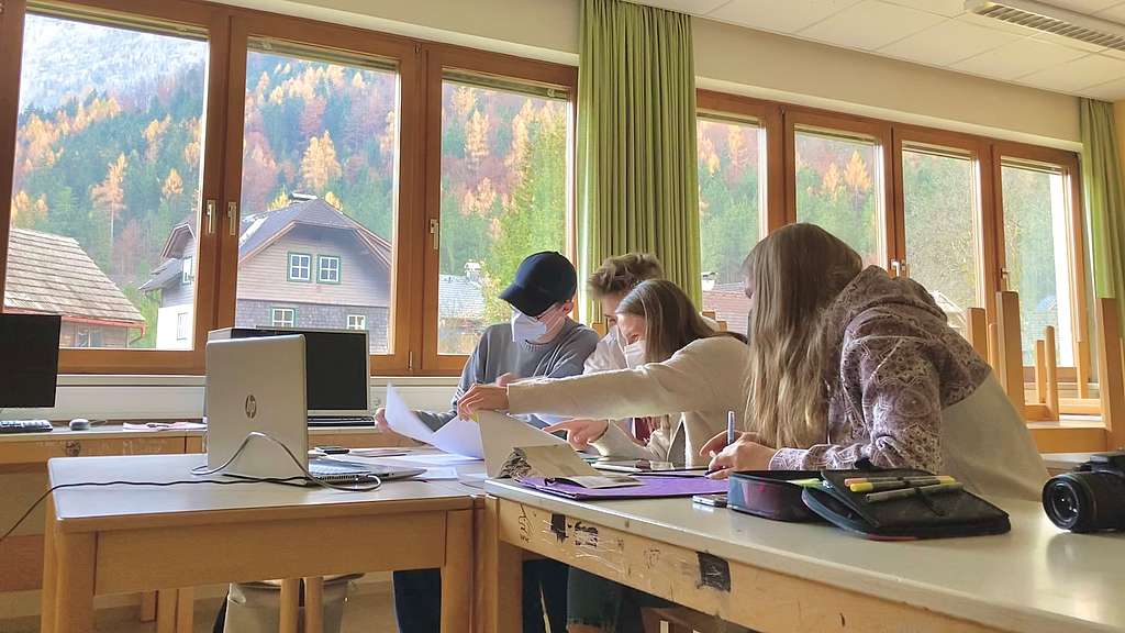 Vier Schüler*innen sitzen in einem Klassenzimmer vor einem Laptop