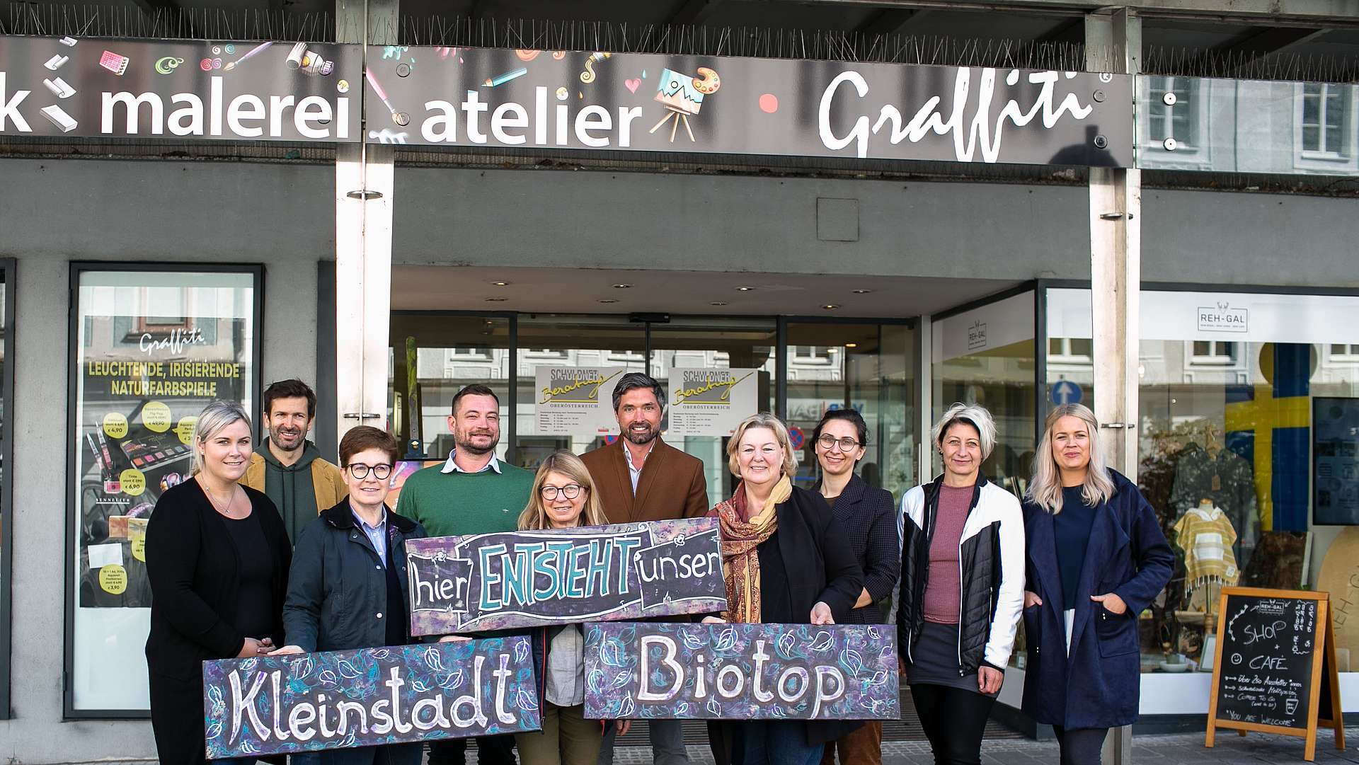 Gruppenfoto mit 10 Personen, mit einem Schild mit der Aufschrift "Hier entsteht unser Kleinstadt-Biotop"