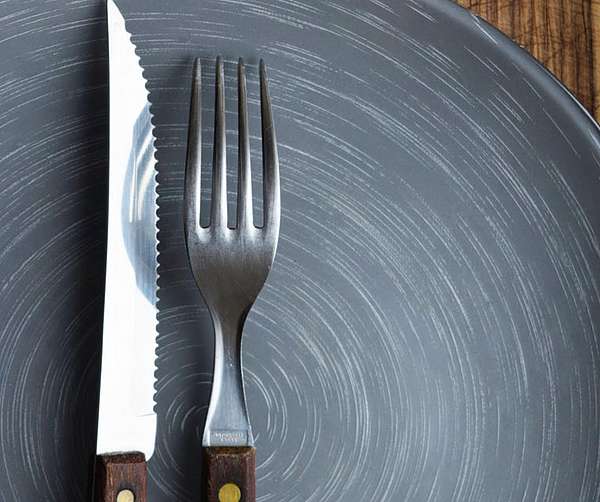 Messer und Gabel liegen auf einem grauen Teller