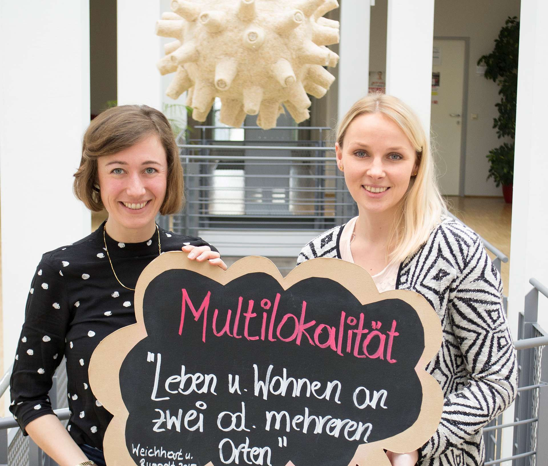 Die Regionalmanagerinnen Steffi Moser und Sandra Schwarz halten ein Schild mit der Aufschrift Multilokalität.