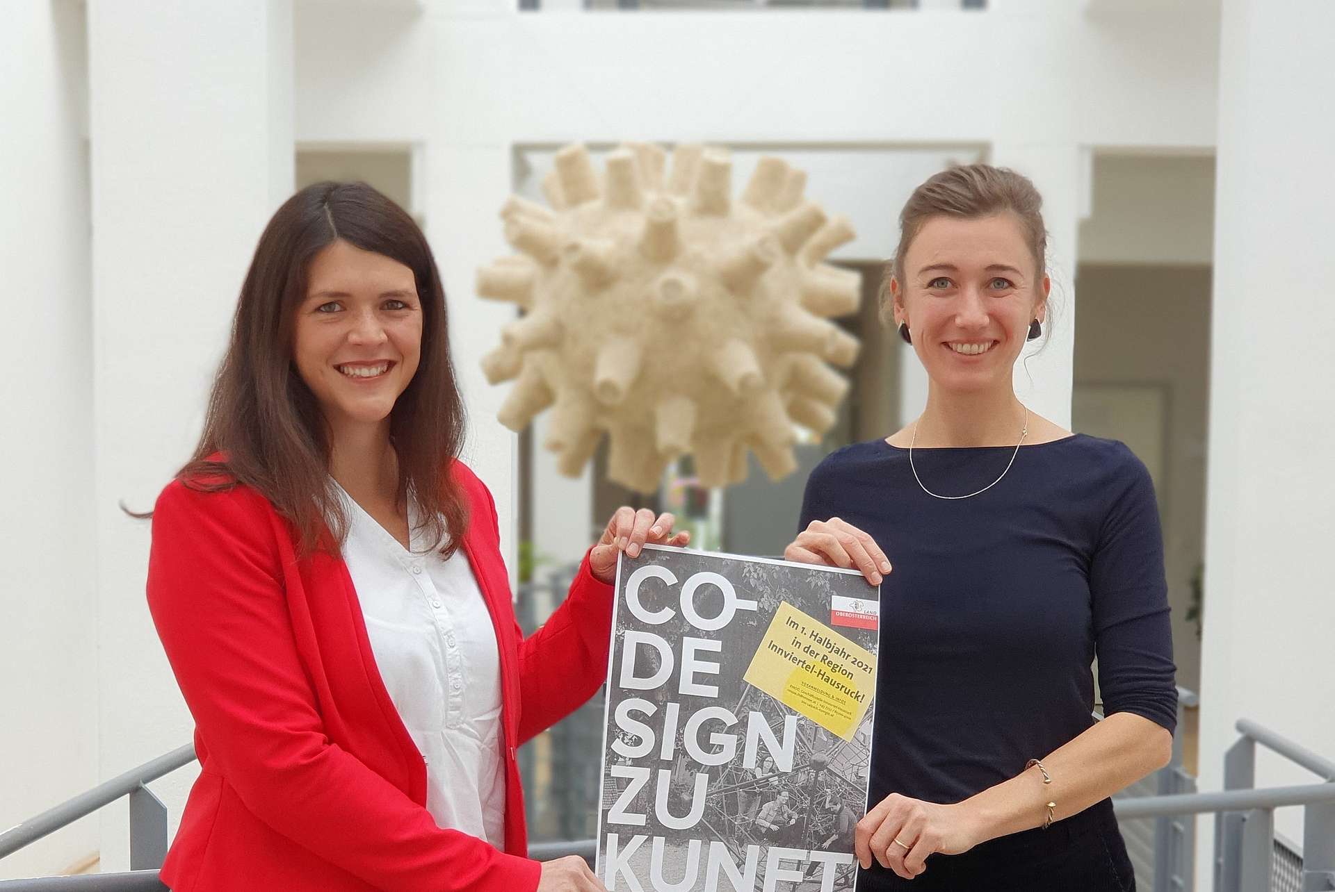 Zwei Frauen halten gemeinsam ein Plakat mit der Aufschrift "Co-Design Zukunft"
