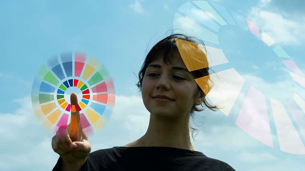 Junge vor blauem Himmel berührt ein virtuelles SDG-Symbol